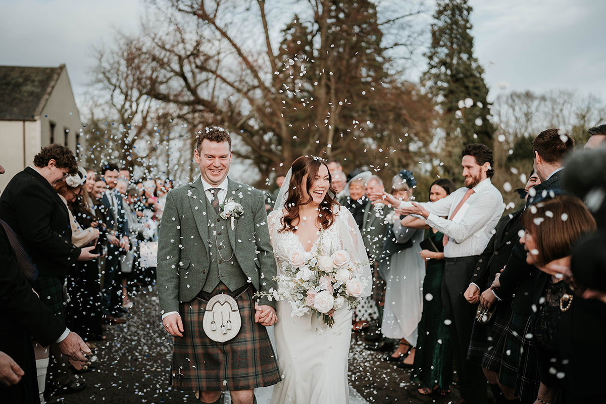 Bride and groom walking through outdoor confetti throw