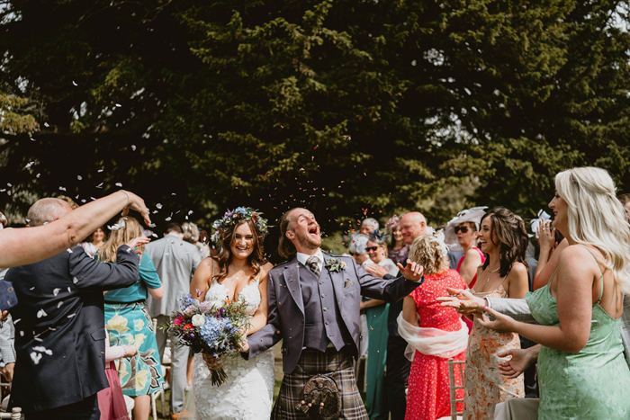 Guests throw confetti at couple as they walk through the crowd