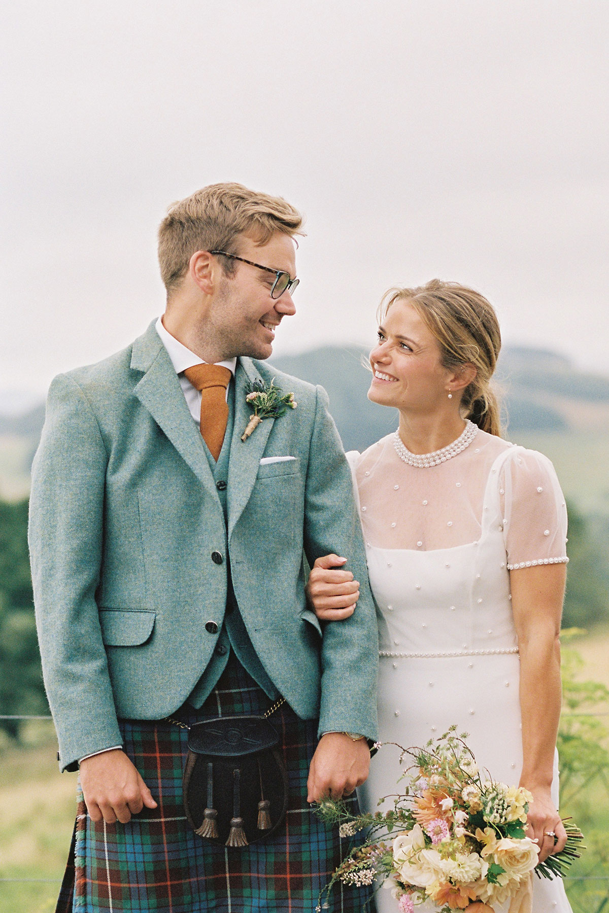 Newlywed couple smiling at each other during a relaxed outdoor wedding portrait in the Scottish countryside.