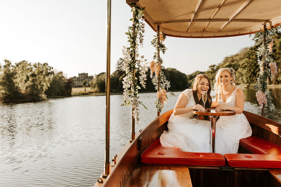 Two brides sit in a boat on the water