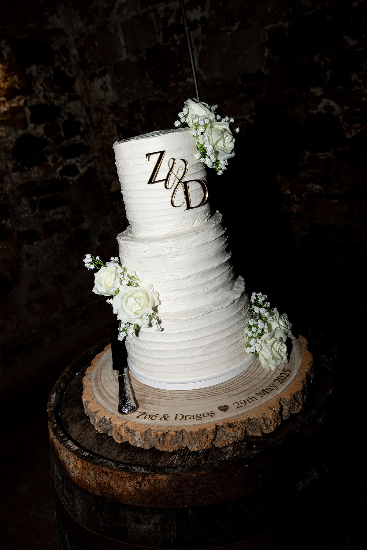 Three-tier white buttercream wedding cake with floral details and gold initials at Falside Mill reception