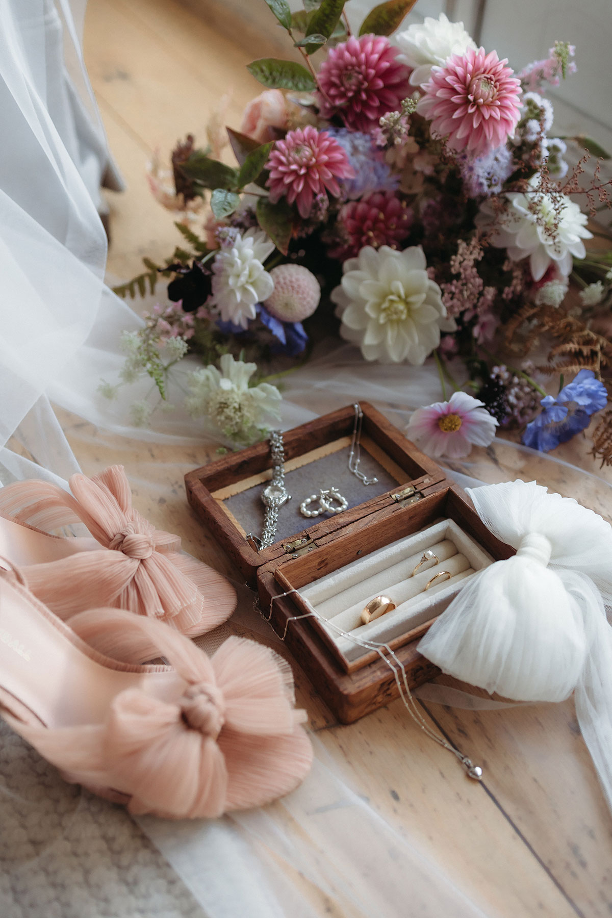 A jewellery box with earrings and shoes next to a bouquet of flowers