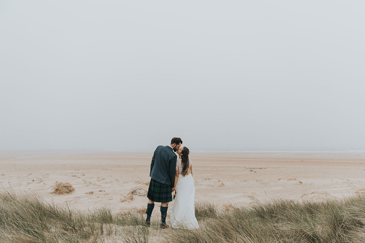 bride and groom kiss as they look towards the ocean at harvest moon weddings