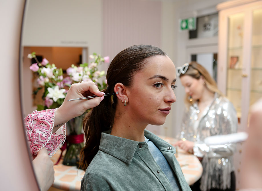 A woman facing side on had an earring held up to her ear