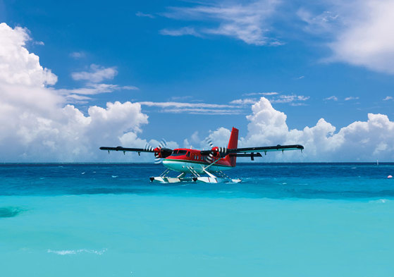 a red sea plane skimming the surface of a crystal blue ocean