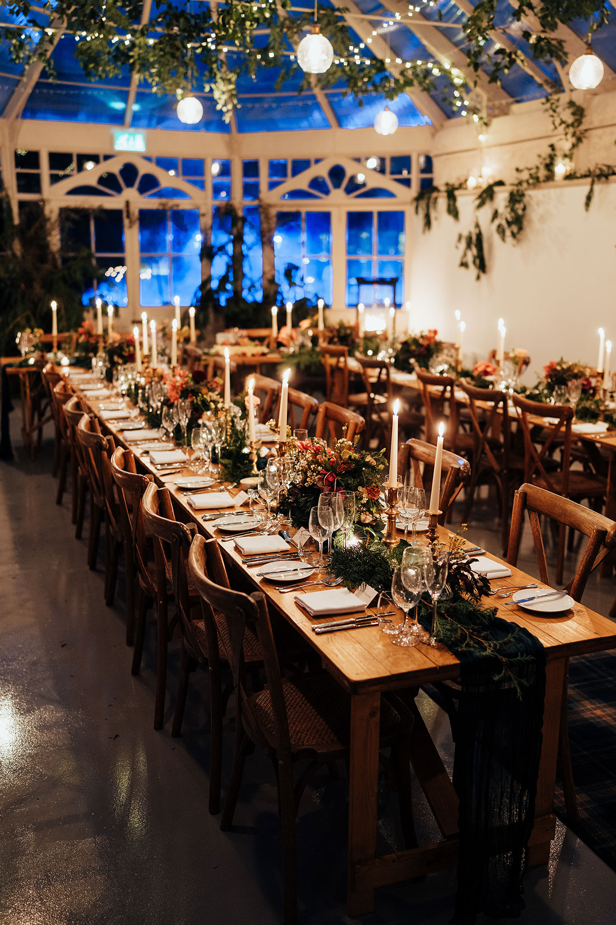 Evening reception set-up in the glasshouse with candlelight and hanging foliage