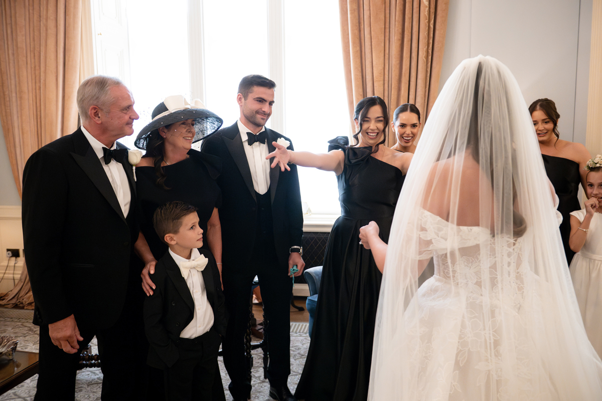Bride revealing her lace wedding dress and veil to family and wedding party ahead of her Crossbasket Castle ceremony.
