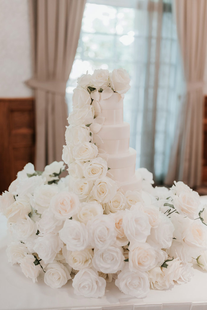 a white wedding cake with cascade of white roses as decoration