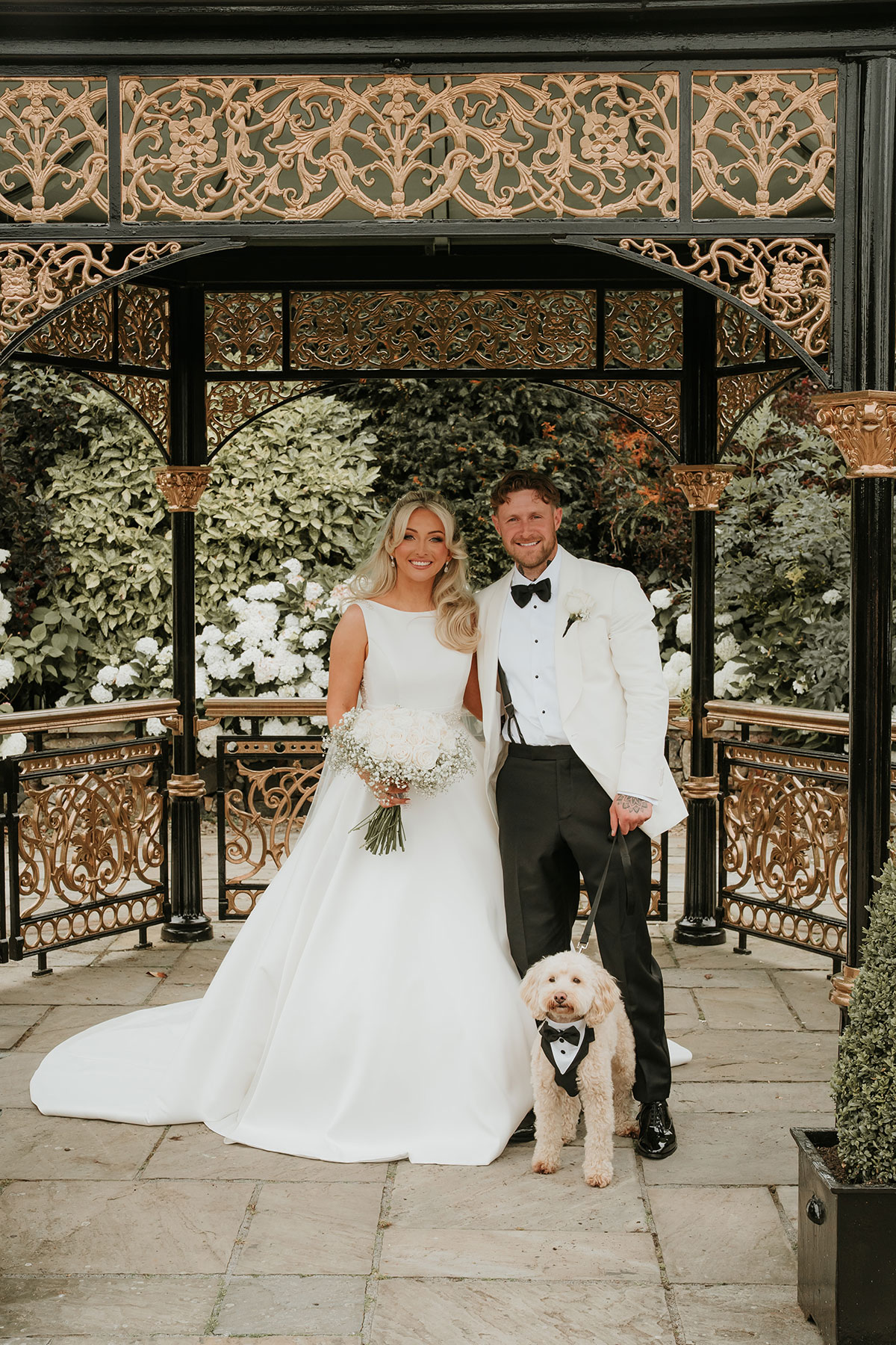 Bride and groom with dog wearing tuxedo at Ingliston Country Club wedding bandstand
