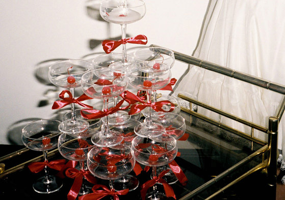 champagne tower of coupe glasses with red bows around the stems, all placed on a cocktail trolley