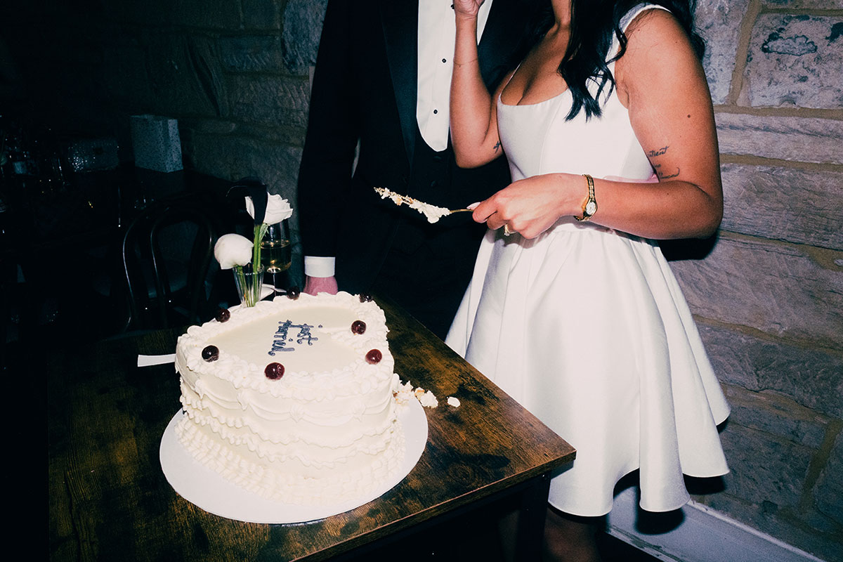 Bride cutting wedding cake at The Haberdashery Glasgow reception with groom beside her