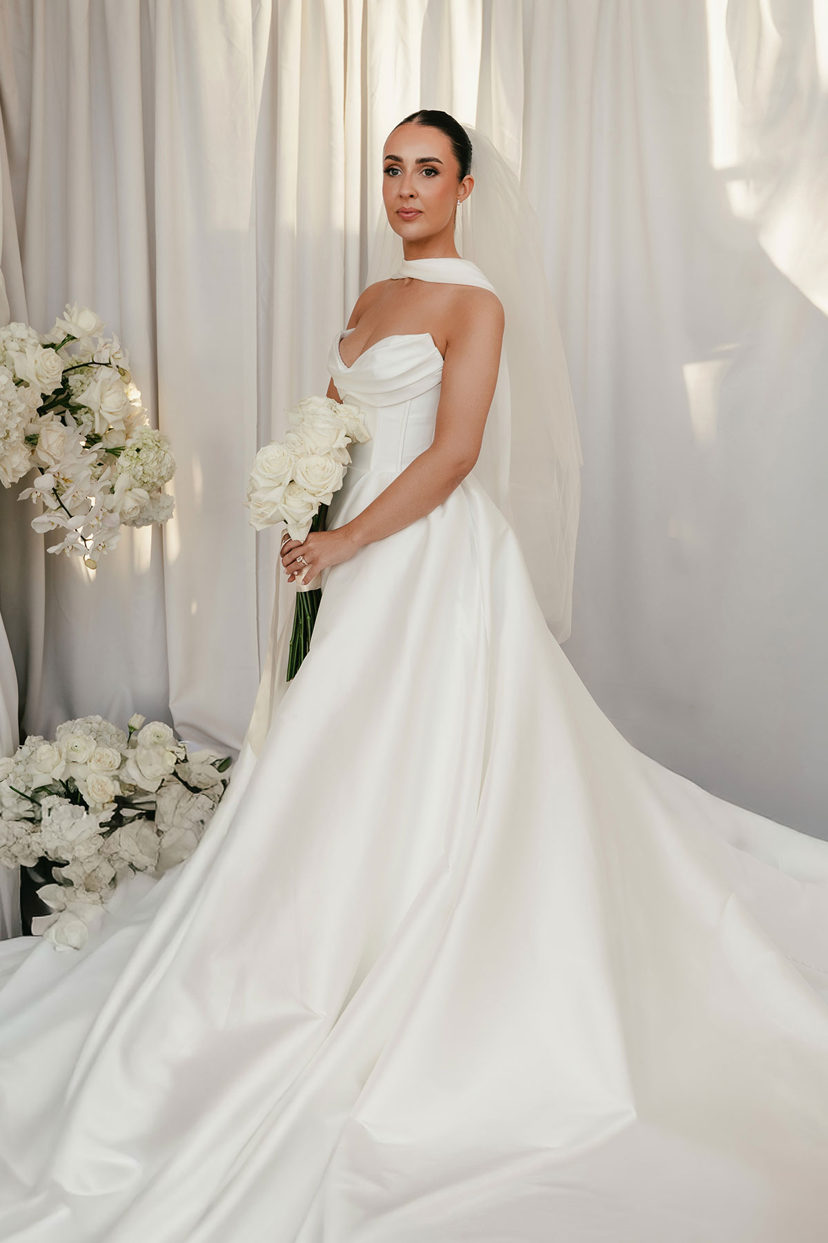 Bride portrait in Justin Alexander wedding dress with veil and white floral arrangements at Enterkine Country House