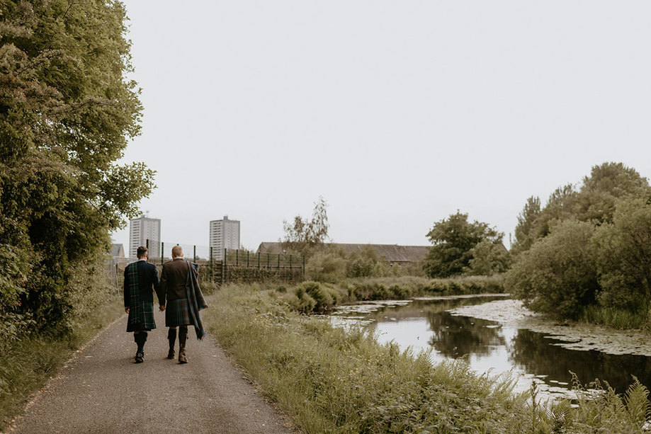 Back Of Two Men In Kilts Walking Along Forth And Clyde Canal In Glasgow