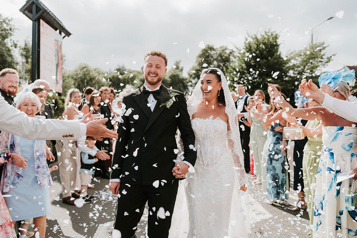 Bride and groom walking through confetti outside The River Inn wedding venue in Renfrewshire.