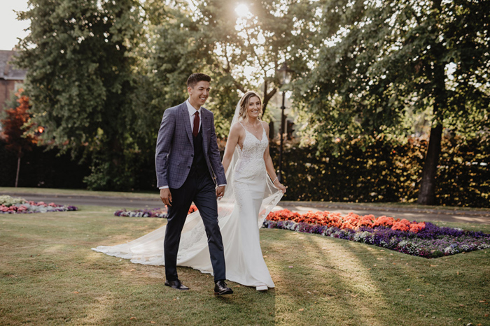 a bride and groom walking through a garden