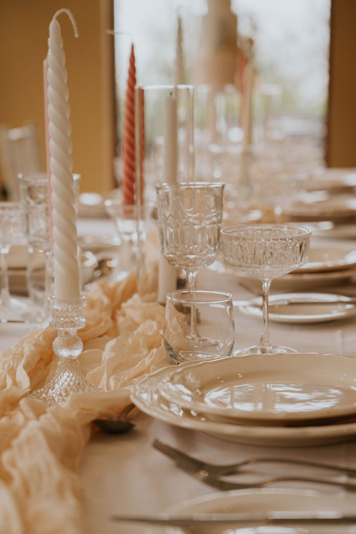 twisted white and pink candles on a table with glassware, crockery and cutlery 