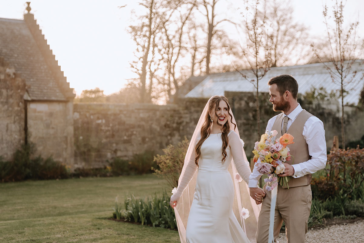 a bride and groom walking hand in hand in gardens of Carlowrie Castle