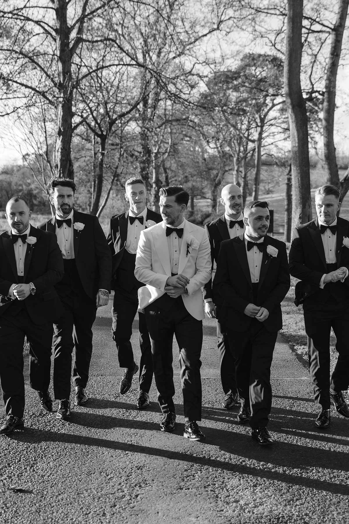 Groom with groomsmen in black tuxedos walking outdoors at Enterkine Country House wedding Ayrshire