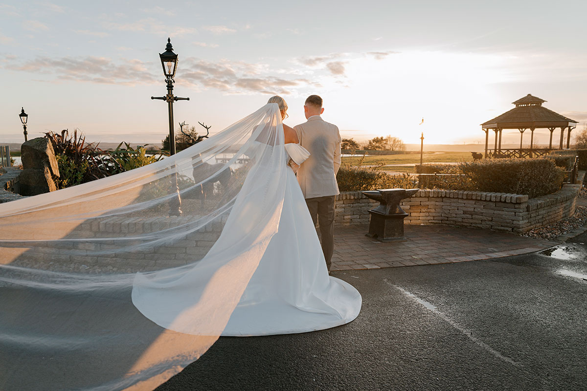 Bride and groom at sunset outside The Vu with waterside views and bandstand in the background