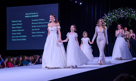 a catwalk with female models wearing wedding dresses and young girl models in frilly dresses too