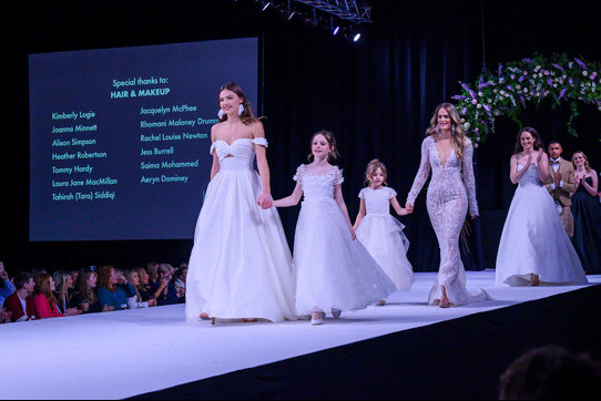 a catwalk with female models wearing wedding dresses and young girl models in frilly dresses too