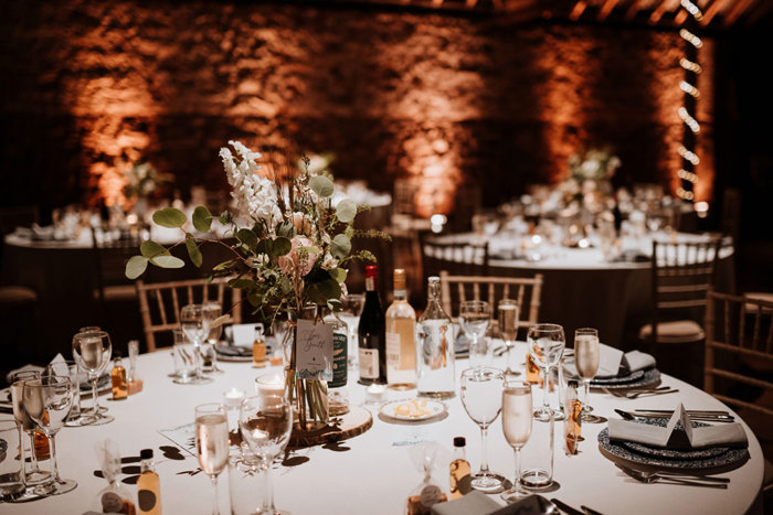 a round dining table in muted lighting with a small medium height bouquet in the centre