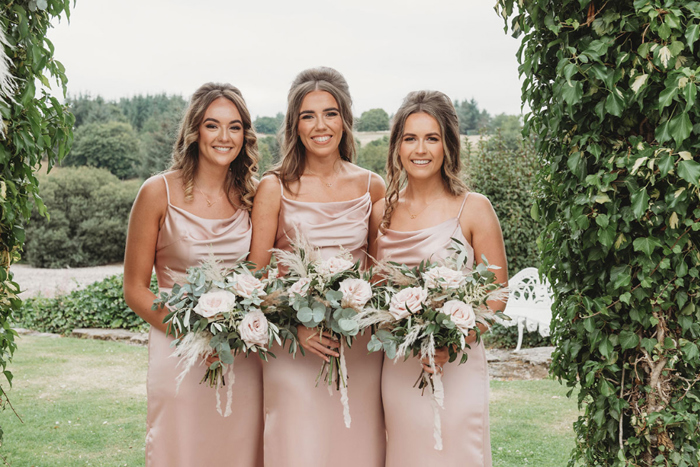 Three bridesmaids in pink dresses holding bouquets