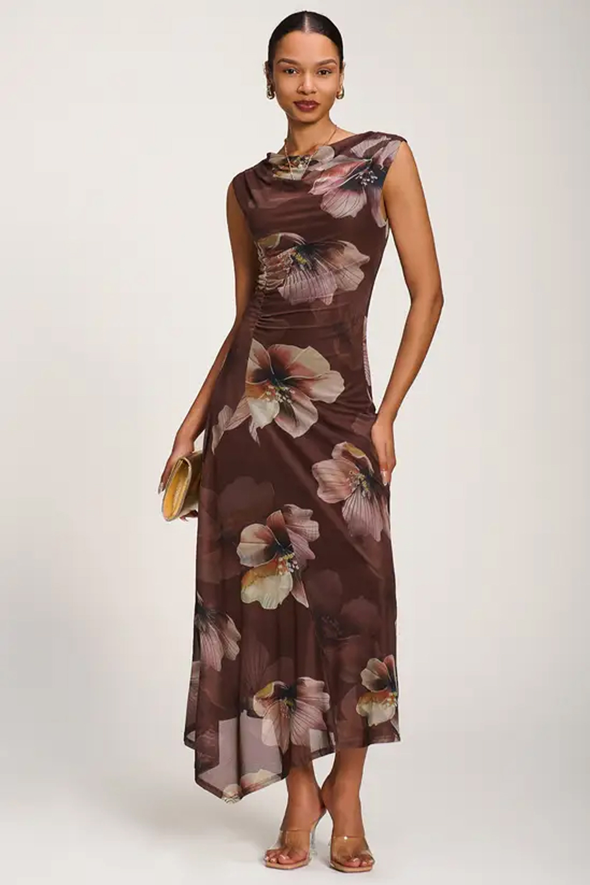 Woman wearing a brown asymmetric floral mesh maxi dress with a draped neckline and ruched waist.