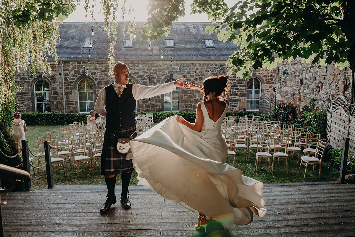 Bride and groom dancing outdoors in courtyard ceremony space at The Venue Eskmills