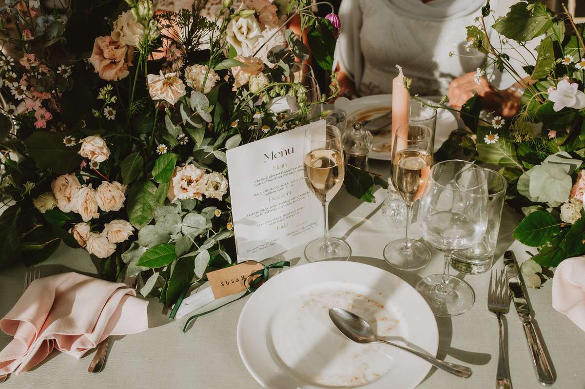 Floral wedding table setting with menu, champagne glasses and pink napkin at Ballogie House