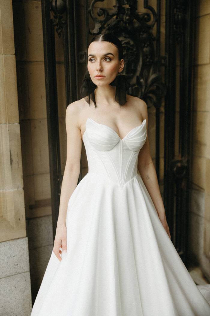 a woman wearing a corset-style wedding dress from Opus Couture with black tulle bow earrings from Gemini Clay Studio.