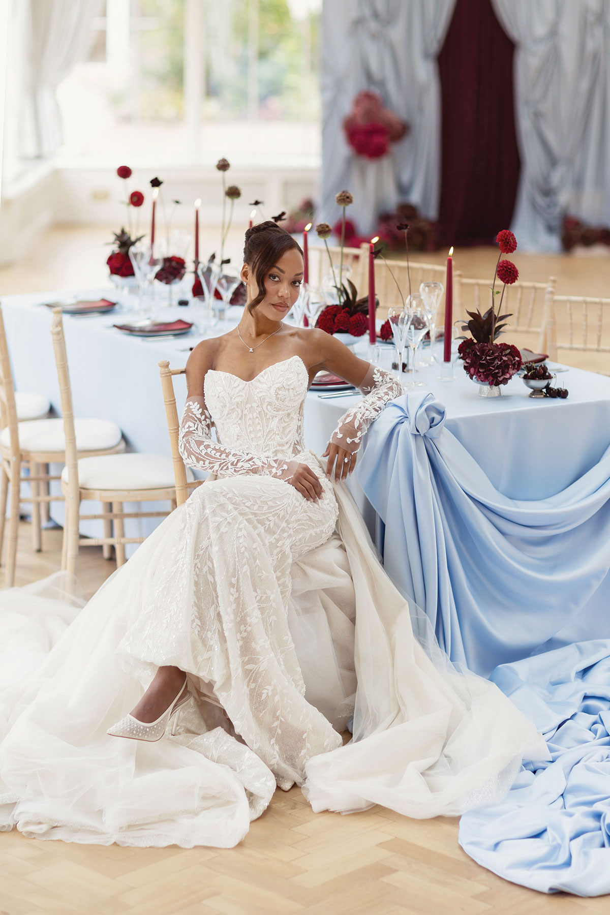 Bride wearing a lace wedding dress beside a powder blue and burgundy wedding table setting at Carlowrie Castle near Edinburgh