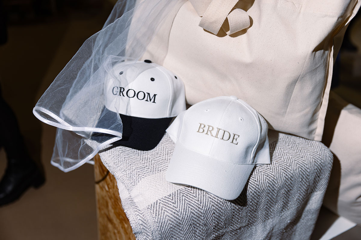 ‘Bride’ and ‘Groom’ embroidered caps with veil detail at a wedding show stand