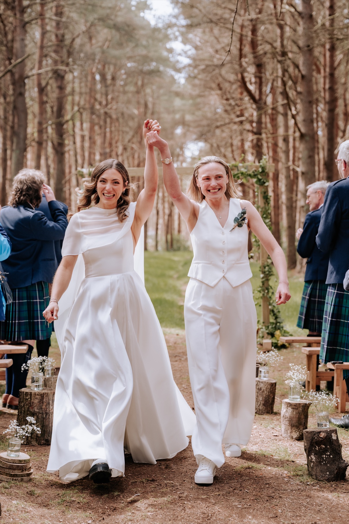 Hannah and Donna celebrating hand in hand as they walk back down the aisle after their Harvest Moon wedding ceremony.