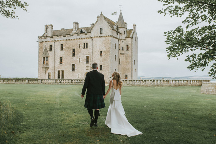 bride and groom walk towards barnbougle castle holding hands