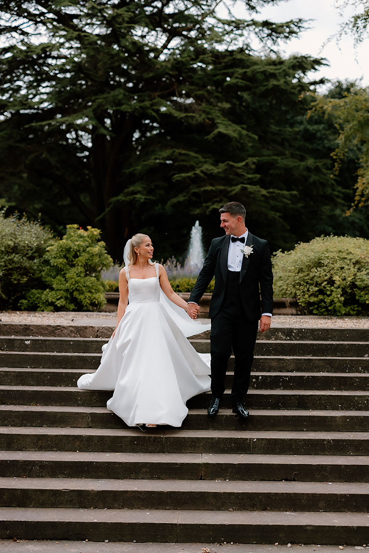 Bride and groom holding hands while walking down the garden steps at Mar Hall.