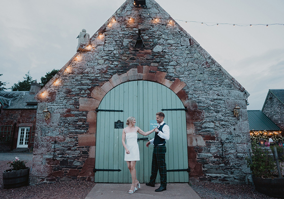 A Bride And Groom Pose By A Green Barn Door At Wedderlie House