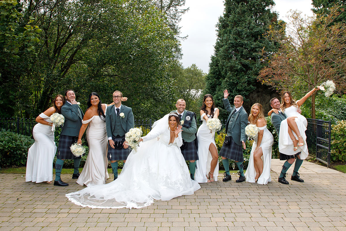 a row of people posing for a photo in front of trees.