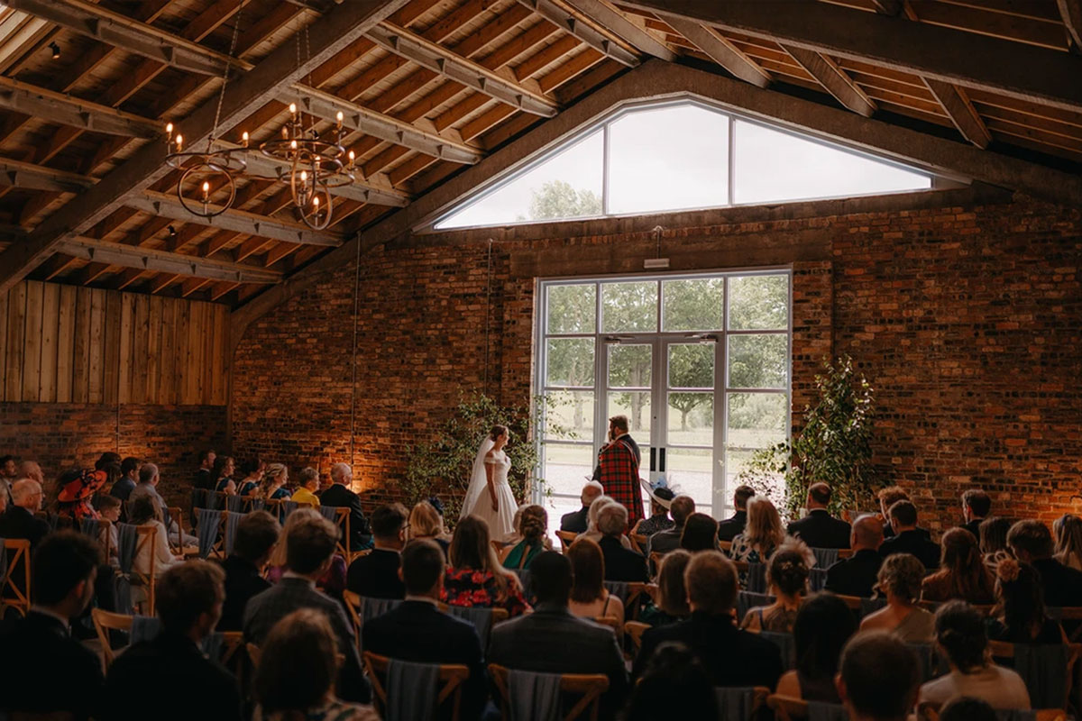 a bride and groom standing in their wedding ceremony inside a stone building with a wooden roof