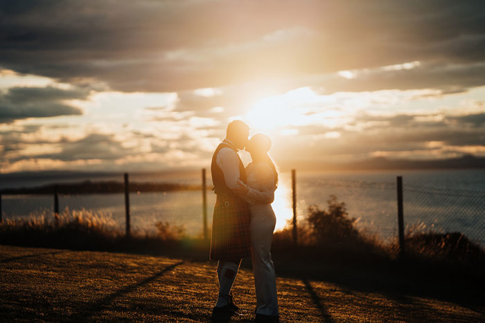 A person and person kissing in front of a sunset.