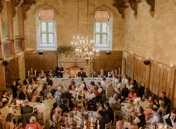 an aerial view of the ballroom at Achnagairn Castle filled with wedding guests seated at round tables as they look towards a rectangular top table