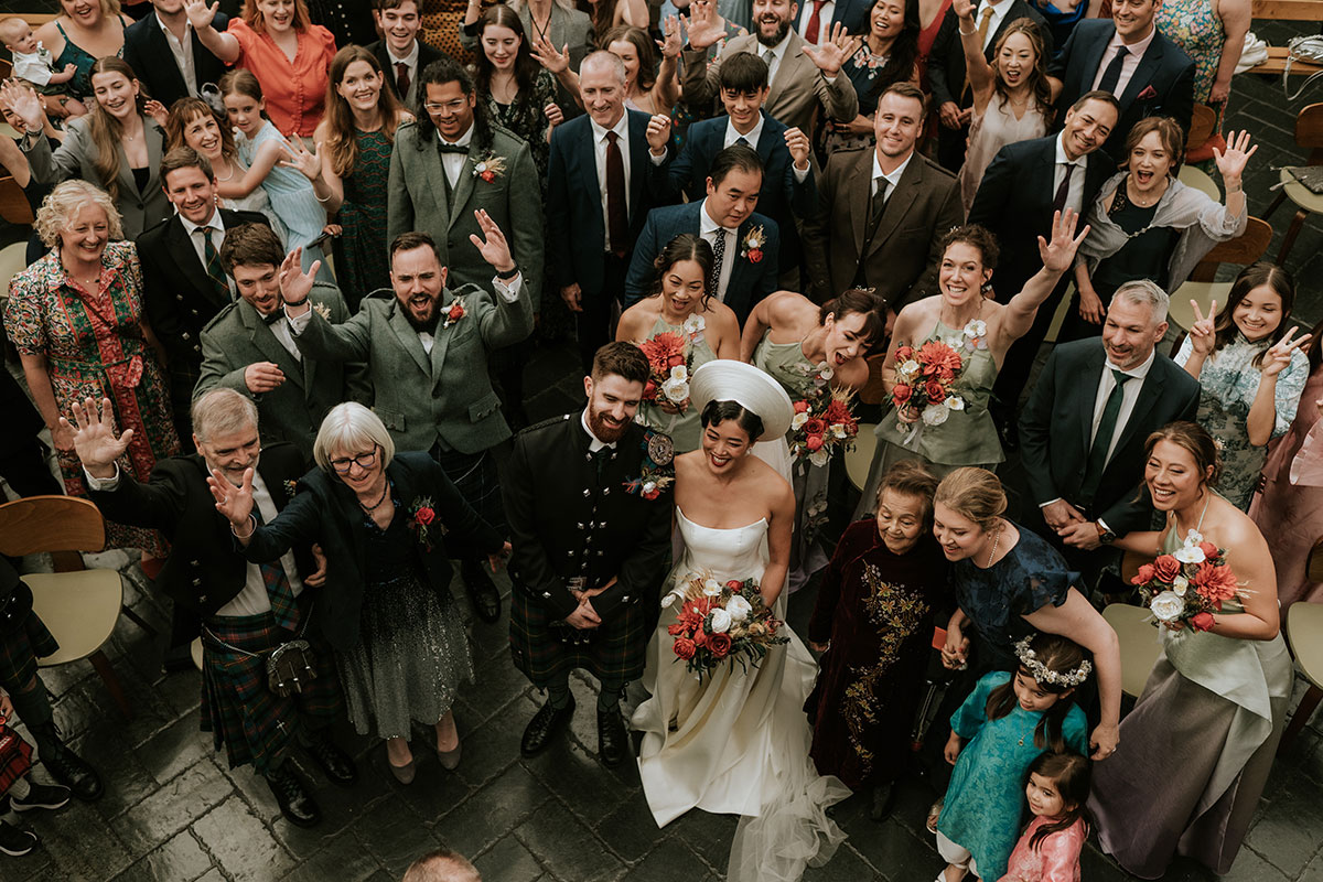 Overhead wedding group photo at BAaD Glasgow with bride, groom and guests celebrating together Full group photo