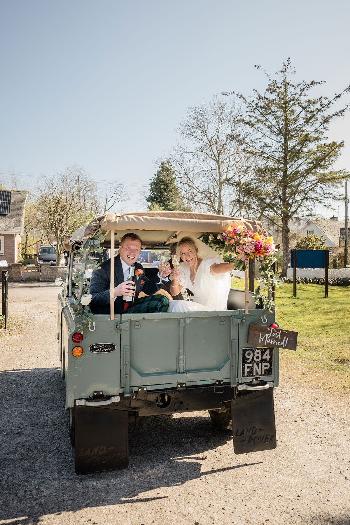 bride and groom share a bottle of champagne inside land rover on wedding day at achnagairn castle