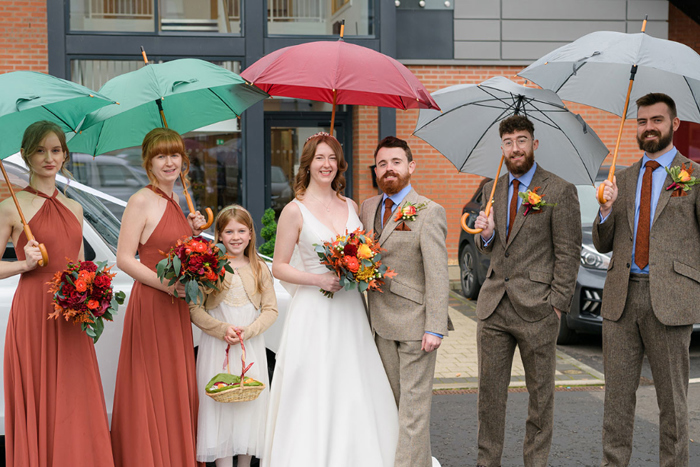 Bride and groom smile in group shot with bridesmaids, groomsmen and flower girl