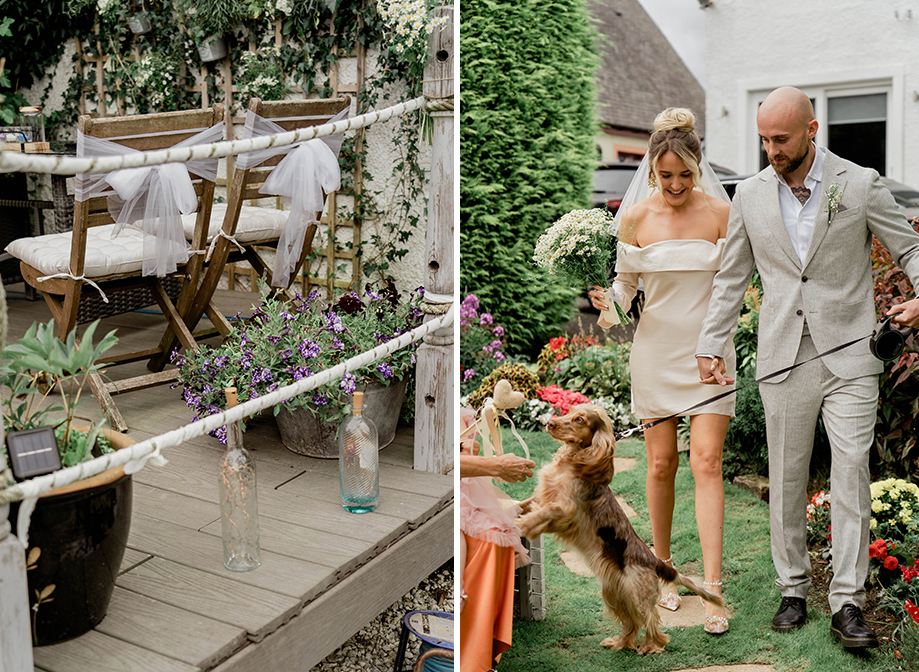 wooden chairs with white tulle bows on wooden decking with plants on left. A bride and groom walking with a spaniel dog in a garden setting