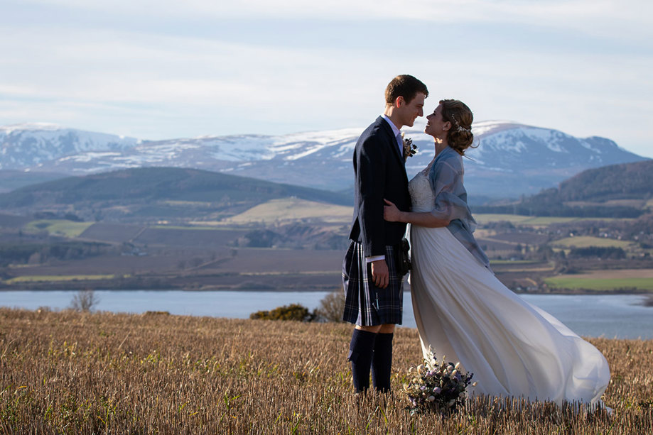 Bride and groom pose with mountain in background