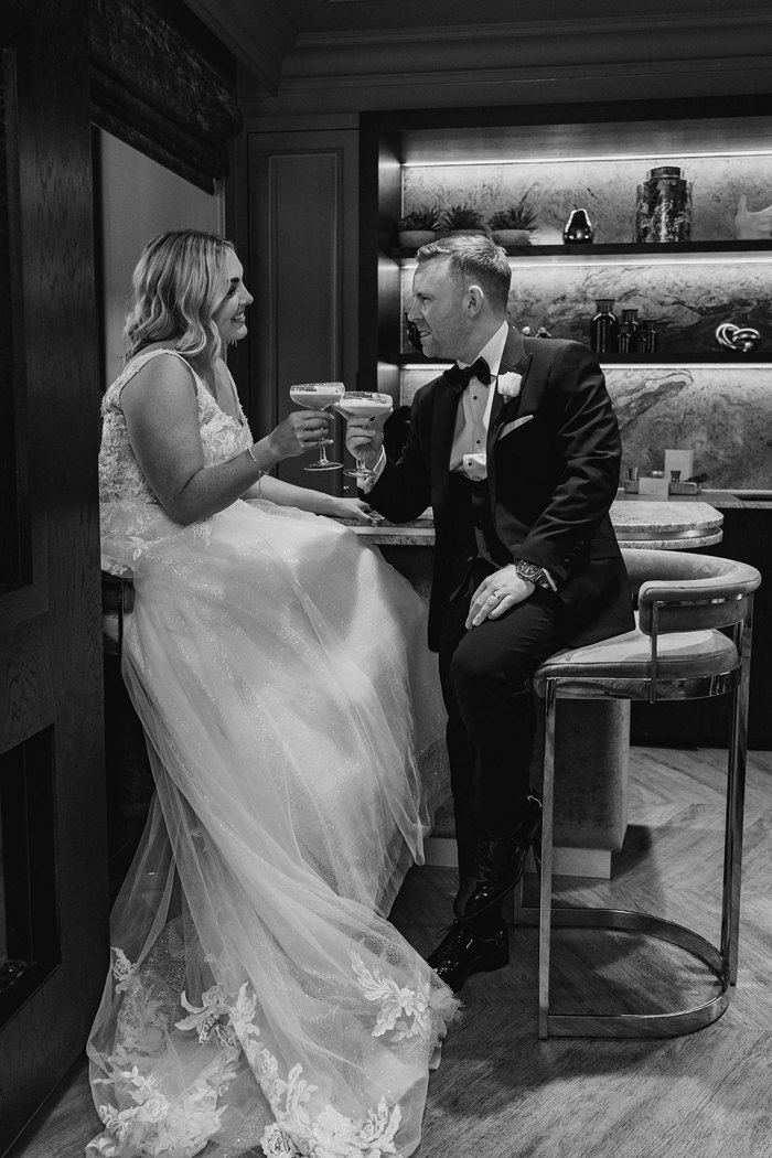 A bride and groom sitting at a table with drinks.