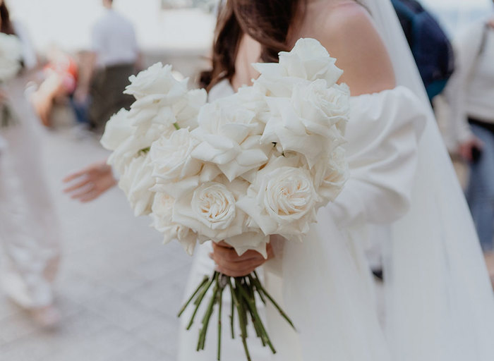 a bride holding a bouquet of white roses with reflexed petals