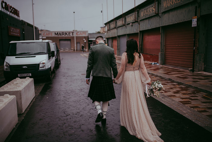 Bride And Groom Walking Along Street At Barras In Glasgow