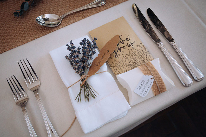 A place setting at wedding dinner with "Let love grow" favour seeds and sprig of lavender